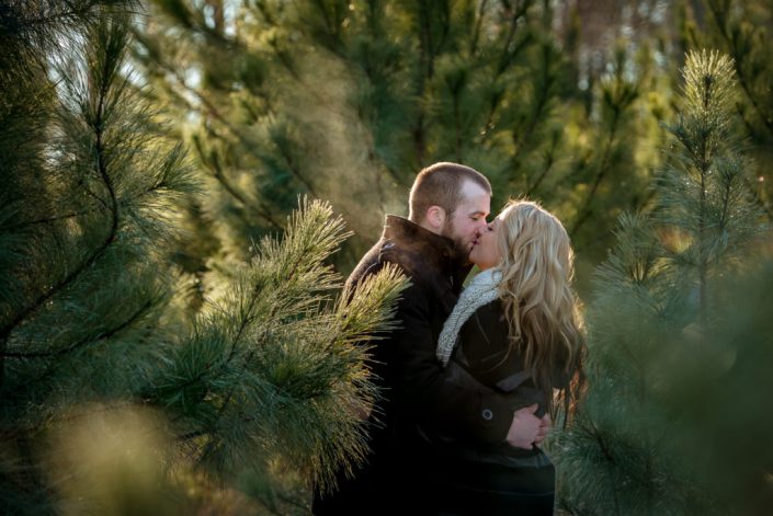 Enagement kiss during a cold winter day in the pine trees