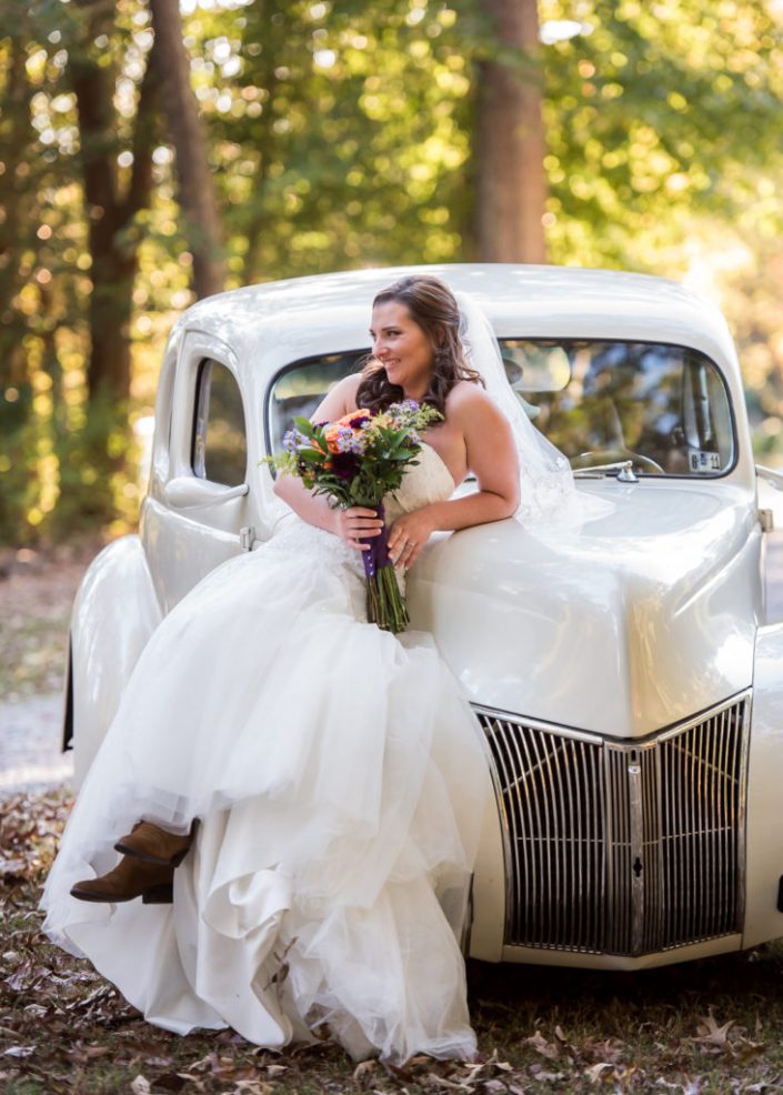 Bride sits on classy white antique car for bridal portrait