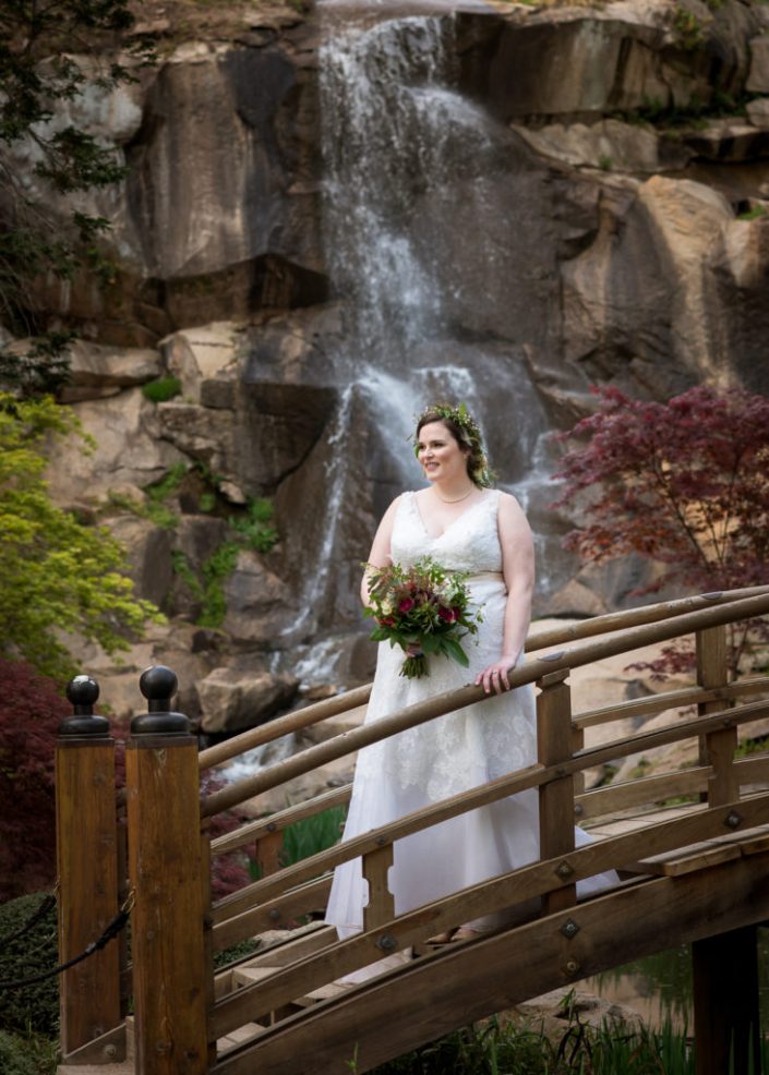 Gorgous bride poses for portrait on bridge with waterfall at Maymont Park, i Richmond, VA