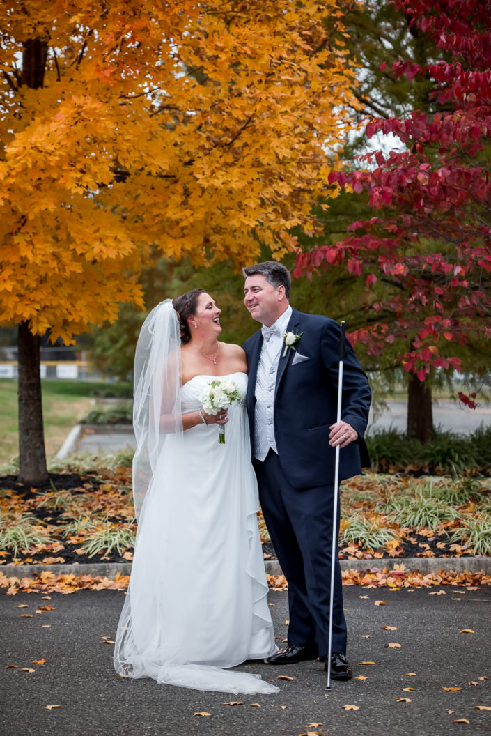 Visually impaired groom poses for portrait with his bride in fall wedding in Ashland VA