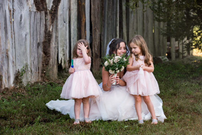 Candid moment with bride and flower girls in front of barn
