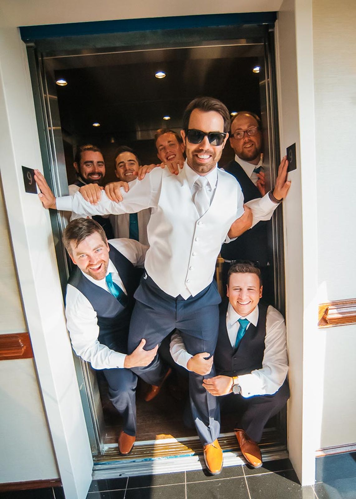 Groomsmen having fun in elevator