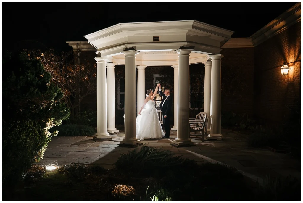 A wedding couple dance under the pergola at night outside of the Robin's Room
