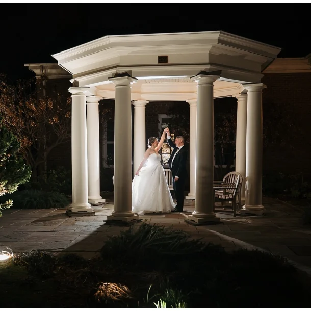 A wedding couple dance under the pergola at night outside of the Robin's Room