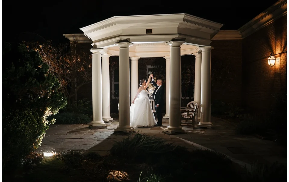 A wedding couple dance under the pergola at night outside of the Robin's Room